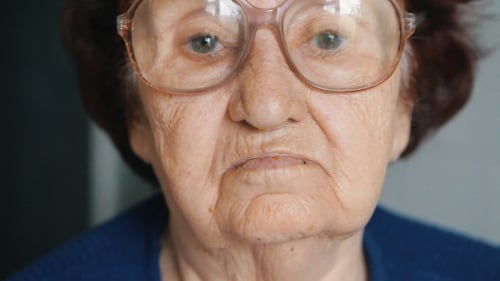 Senior Woman Puts on Her Glasses Close Up