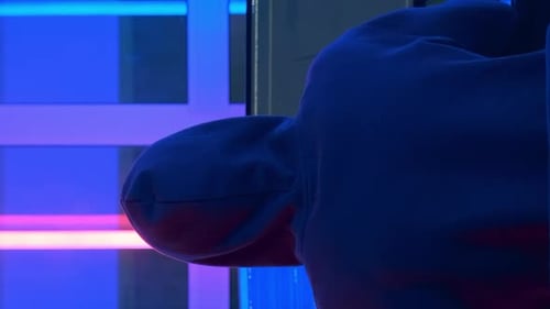 Vue arrière d'un hacker dans une veste noire et une capuche sur la tête, écrivant des programmes de hacker