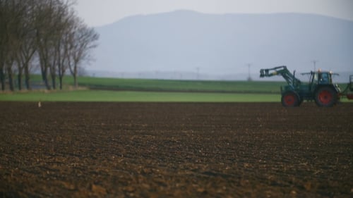 Traktor arbeitet bei Sonnenuntergang auf dem Feld