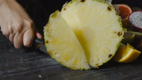 Cutting Pineapple in Half on Wooden Table