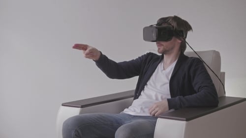 Man Experiencing Virtual Reality with VR Headset in Chair