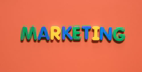 Hands Spelling Marketing with Colorful Foam Letters