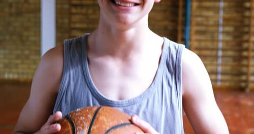 Schoolboy standing with basketball in court 4k
