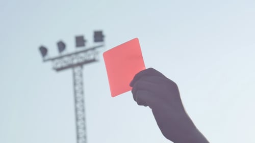 Hand Holding Red Card Against Sky