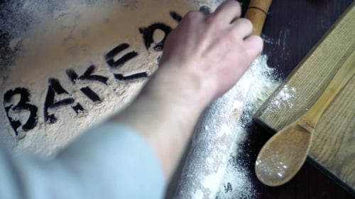 Inscription Bakery On White Flour Spills On The Kitchen Table. Bakery Concept