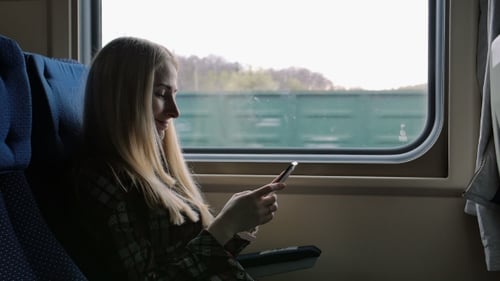 Junge Frau nutzt Smartphone auf Reisen mit dem Zug