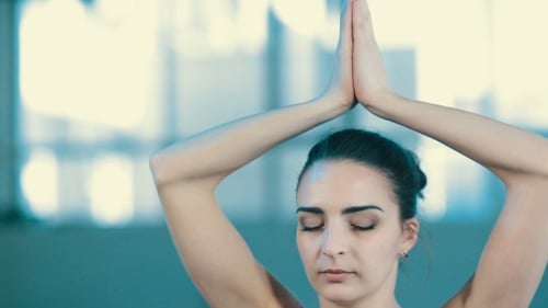 Calm Woman Meditating Indoors with Hands Above Head