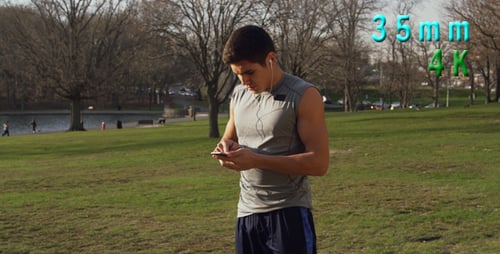 Man Running, Checking Phone in the Park