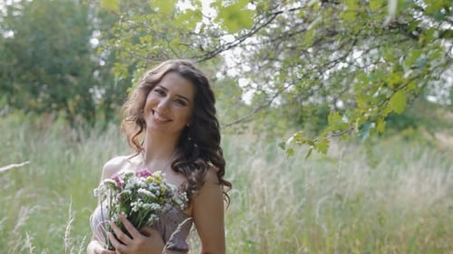 Smiling Woman Holding Flowers in a Grassy Field