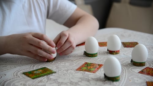 Child Decorates Easter Eggs at Table