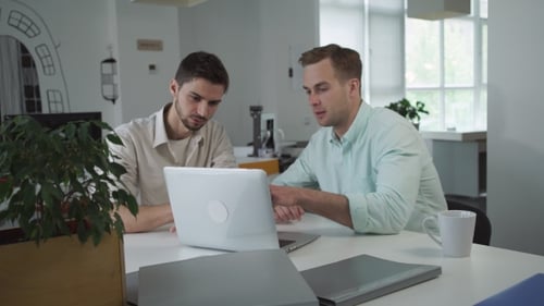 Two Young Adults Collaborating at Desk with Laptop