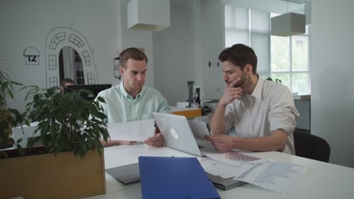 Two Young Men Collaborating in Office with Data