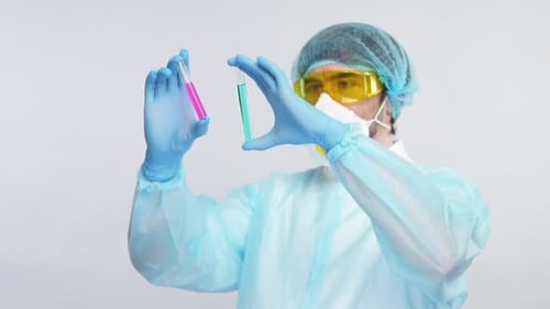 Químico sostiene tubos de ensayo con reactivos y los compite en un traje de protección