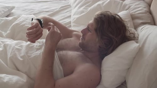 Man Wakes Up and Uses Smartwatch in Bed