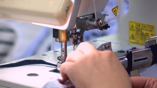 Factory Seamstress At Work And Industrial Sewing Machine