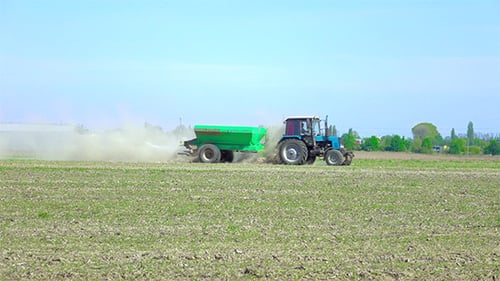 Tractor Spreads Fertilizer Across a Rural Field