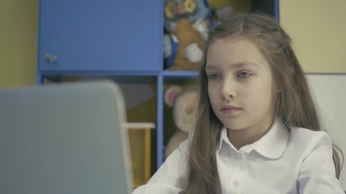 Young Girl Using a Laptop And Doing Homework In School