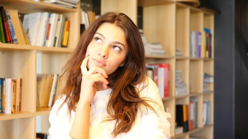 Young Woman Thinking in Front of a Bookcase
