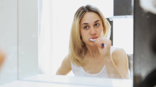 Woman Brushing Teeth in Bathroom Mirror, Daily Routine