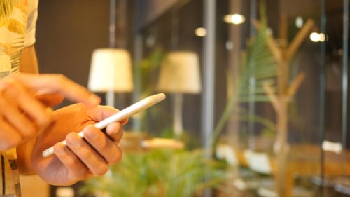 Person Uses Smartphone Indoors in Warm Light