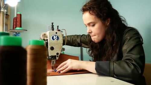 Beautiful Seamstress Sews a Pocket To a Leather Bag in a Sewing Workshop. A Woman Operates Sewing