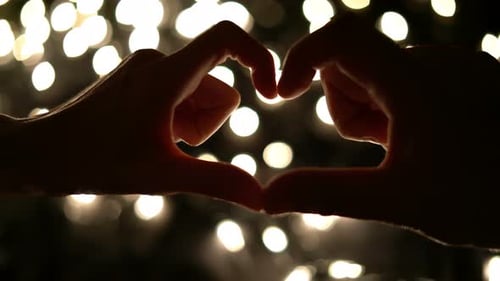Hands Form Heart Shape Against Bokeh Lights