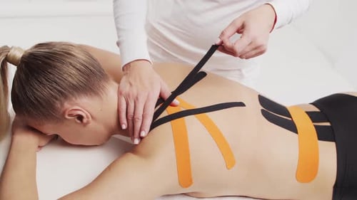 Woman Receiving Kinesiology Tape Treatment on Back