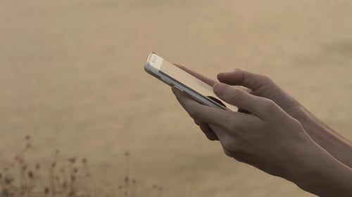 Hands Using Cellphone At Golden Hour In Nature