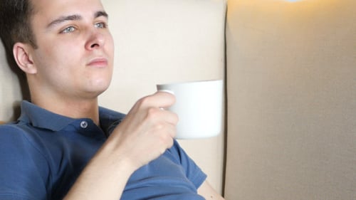 Young Adult Relaxing on Couch with White Mug