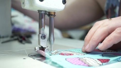 Factory Seamstress At Work And Industrial Sewing Machine