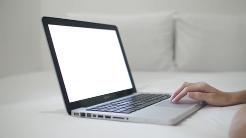Laptop on Bed with Hand Typing on Trackpad