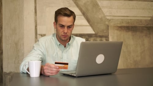 Man Uses Laptop and Credit Card at Table