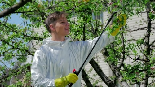 Hübscher Kerl, der Chemikalien im Garten versprüht