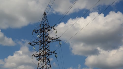 Electrical Transmission Tower Against Blue Sky and Clouds