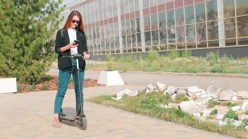 Woman on Electric Scooter Checking her Phone