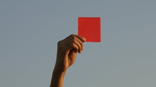 Hand Holds Up a Red Card in Sky