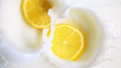 Two Lemon Pieces Drop Into Milk
