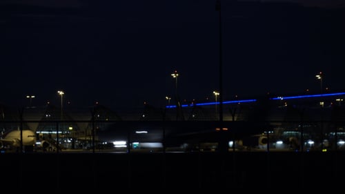 Airplanes at Airport at Night Behind Fence