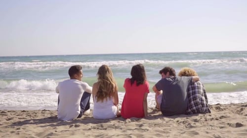 Young People Sitting On The Beach.