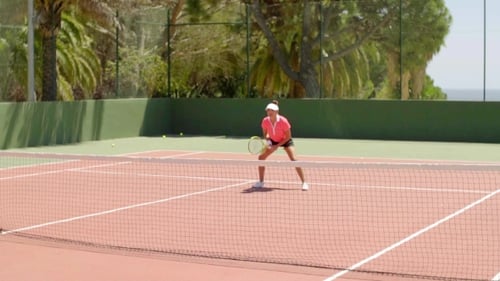 Active Woman Playing Tennis on Tropical Court