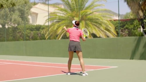 Woman Practices Her Tennis Serve on Sunny Court