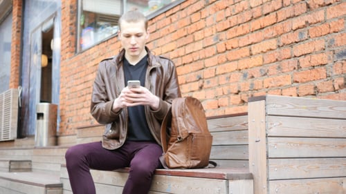 Young Adult Using Phone on Urban Bench