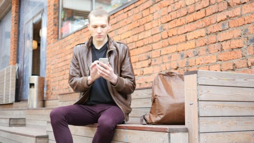 Young Adult Using Smartphone on City Bench