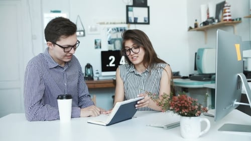 Side View Of Smiling Business Colleagues Working On Laptop