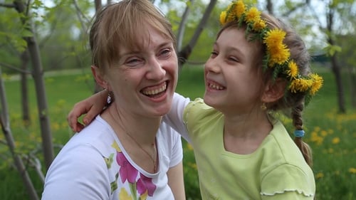 Mother and Daughter Embrace in Park with Flowers