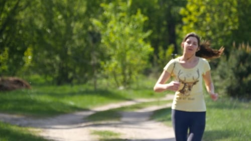 Girl Running on Forest Path in a Park and Taking Breath After Jogging.