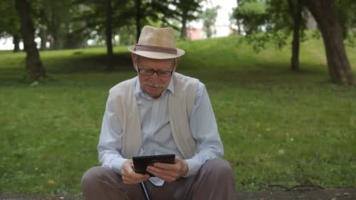 Senior Man Using Tablet in Park Setting
