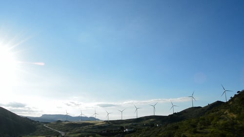 Wind Turbines Spinning on a Grassy Hillside