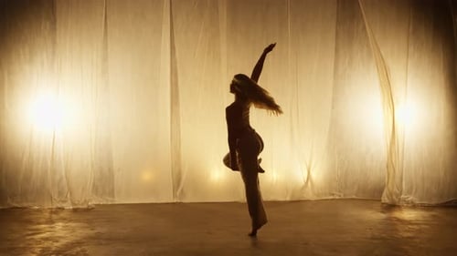 Silhouette of a Professional Dancer Performing in Studio in Soft Warm Lighting