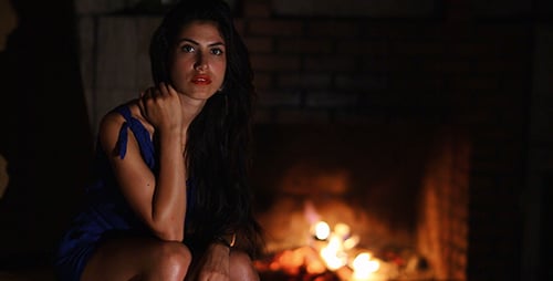 Elegant Woman Sits in Front of Fireplace